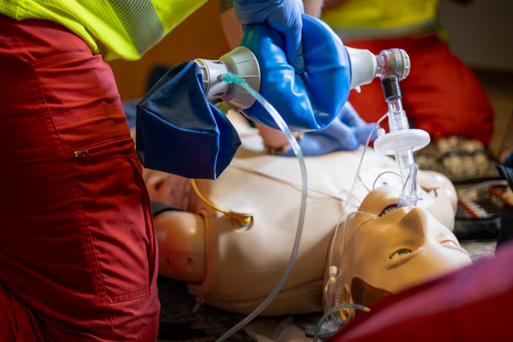 Paramédico y doctor realizando RCP con ambú en maniquí durante curso de reanimación cardiopulmonar